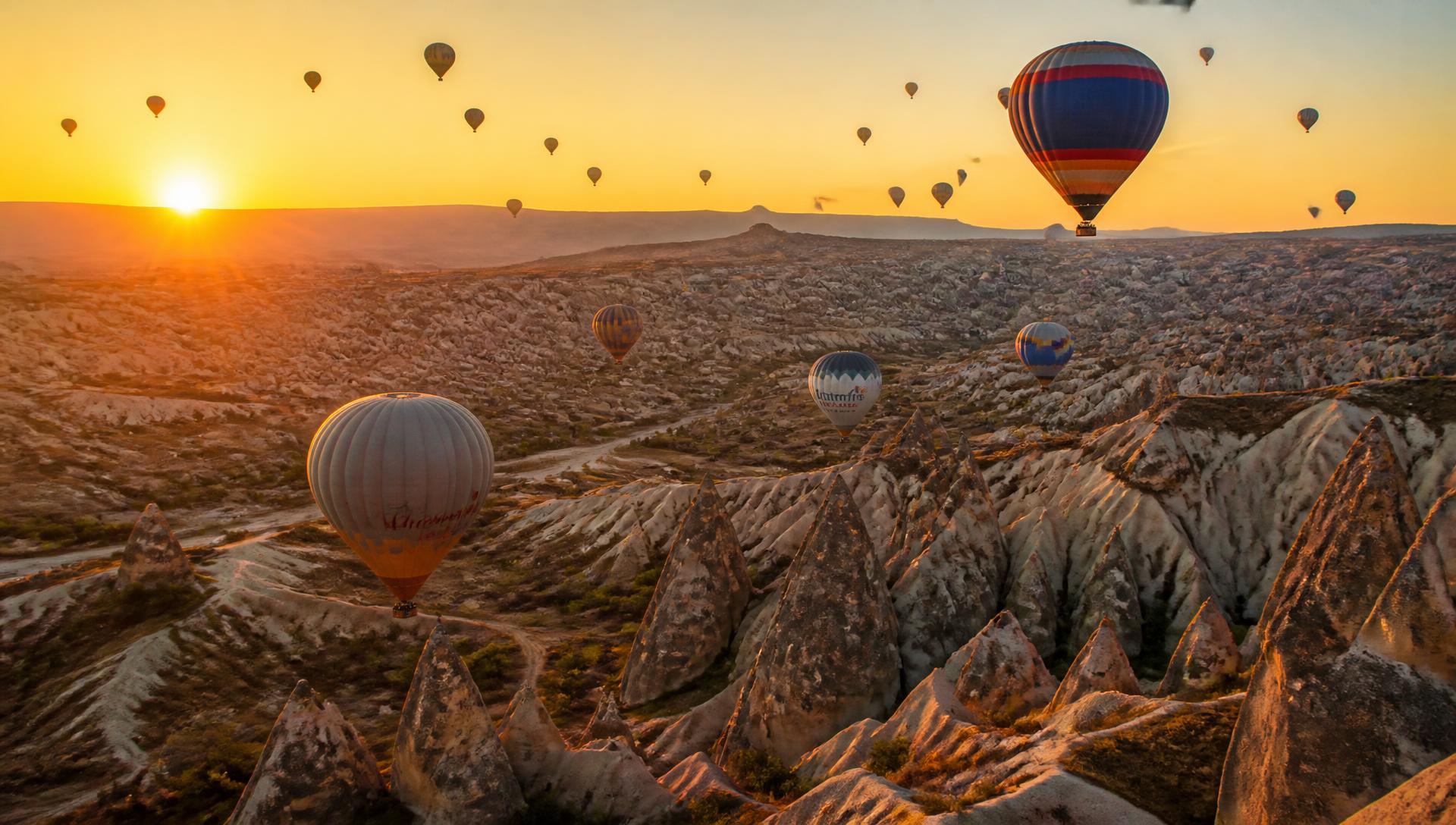 Hot air balloons rising over the fairy chimneys of Cappadocia at sunrise